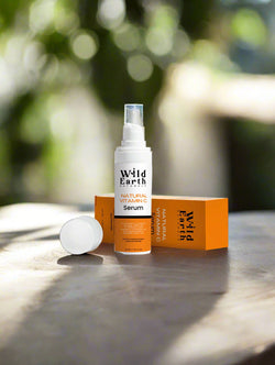 Wild Earth serum bottle and packaging on a white surface with greenery in the background