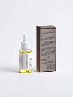 Skincare serum bottle with dropper and its packaging on a light gray background