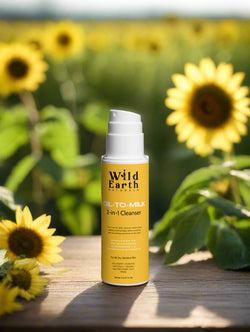 Yellow bottle of Wild Earth Oil-to-Milk 3-in-1 Cleanser on a brown background with natural elements.